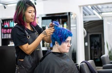 Hairdresser dyeing client's hair at hair salon