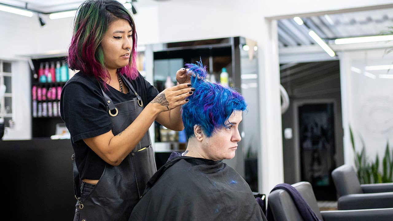 Hairdresser dyeing client's hair at hair salon