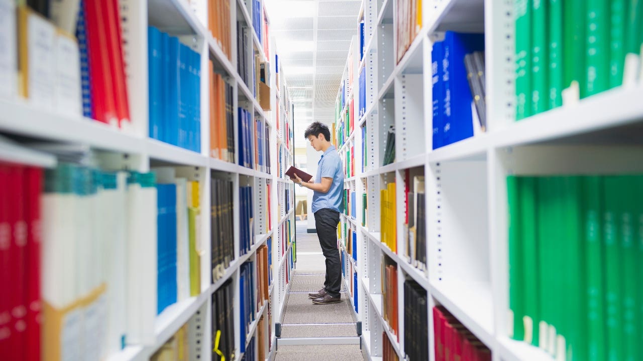 Student stands between stacks in a library