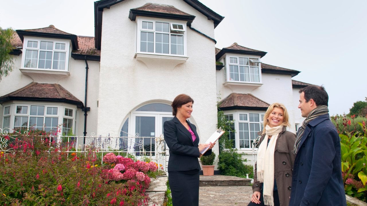 Potential homebuyers standing in front of a house along with a real estate agent