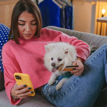 A beautiful young woman is shopping online using a mobile phone