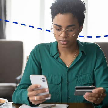 woman using smartphone with credit card in hand