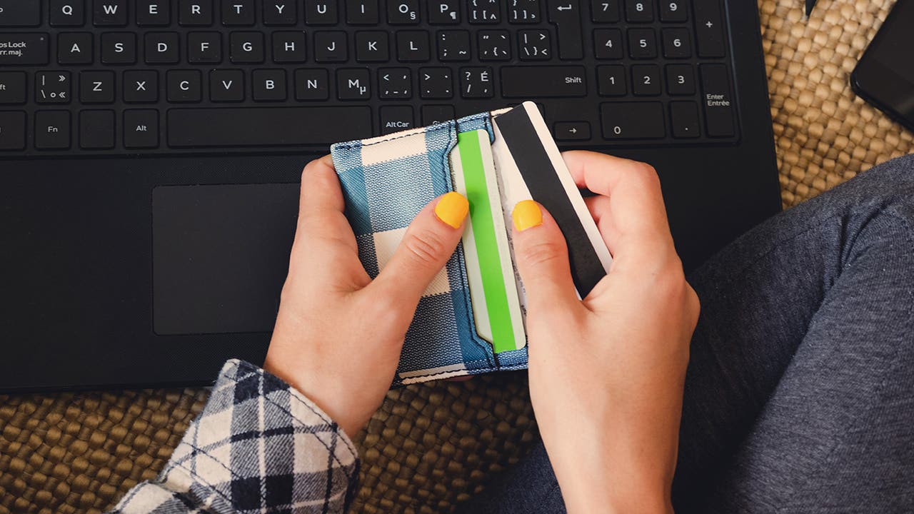 Young woman shopping online takes out her credit card from her w