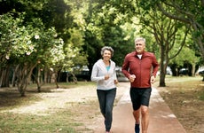 An older couple is jogging in a park