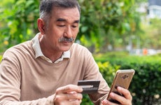 Elderly man is paying online by using smart phone and credit card