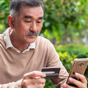 Elderly man is paying online by using smart phone and credit card