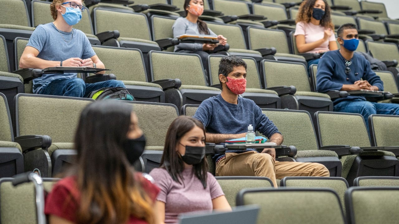 College student sits in lecture with a mask on