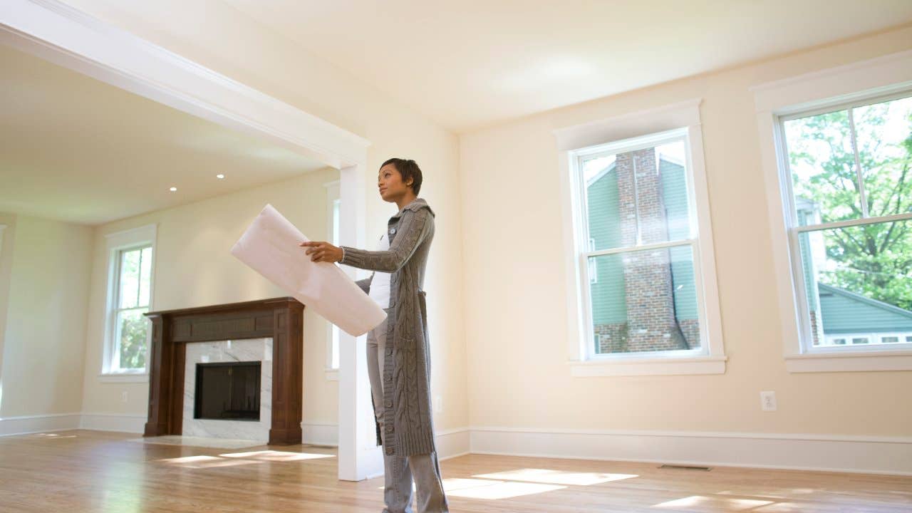 Appraiser looking at a large piece of paper in an empty living room space