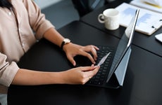 woman typing and holding credit card in front of monitor