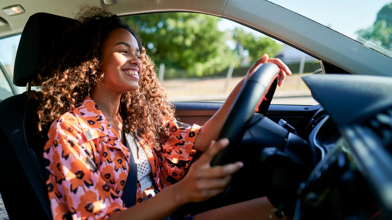 Woman smiling and driving car on a sunny day