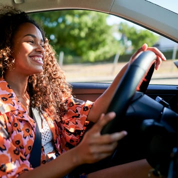 Woman smiling and driving car on a sunny day