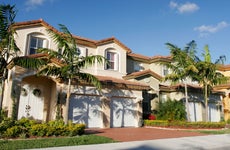 Houses in Florida on a sunny day against the blue sky with palm trees in the front lawn.