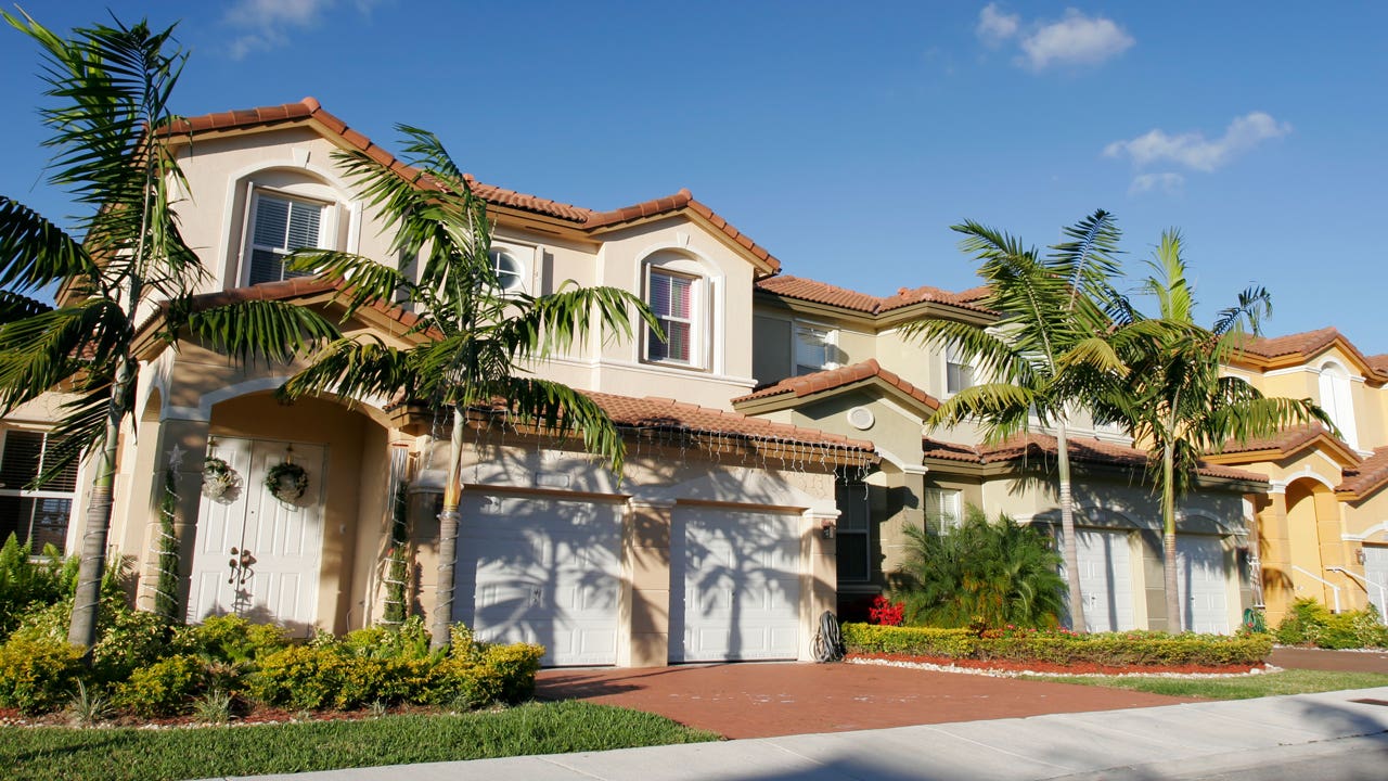 Houses in Florida on a sunny day against the blue sky with palm trees in the front lawn.