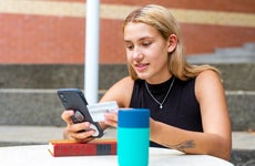 young women on her phone and holding a credit card