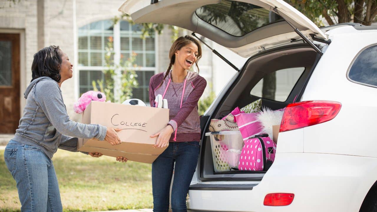 Mother helping daughter move boxes into car for college