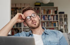 Man on laptop looking to side contemplatively