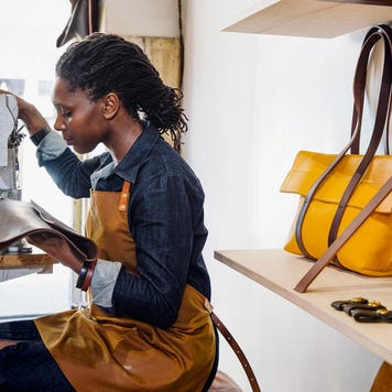a women is sowing leather in a shop
