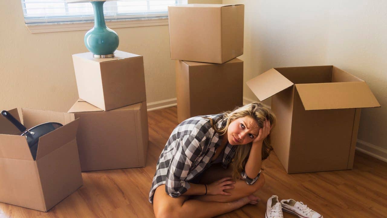 Woman surrounded by cardboard boxes appearing distressed