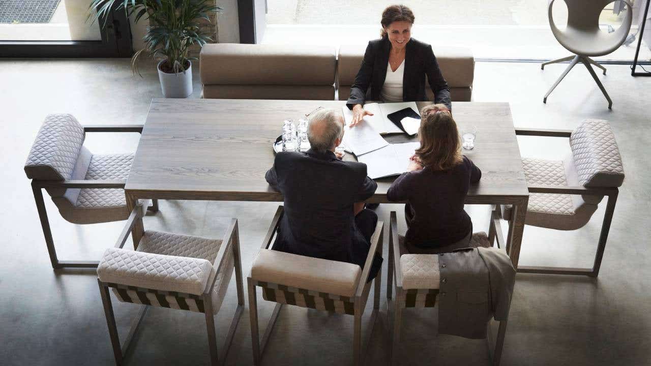 High angle view of female lawyer and customers sitting at desk in office