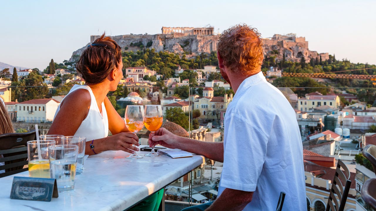 couple cheering glasses overlooking the parthenon in Greece