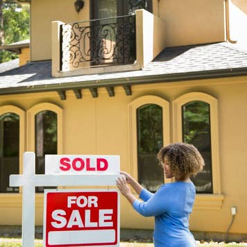 Real estate agent placing a "sold" sign on a home