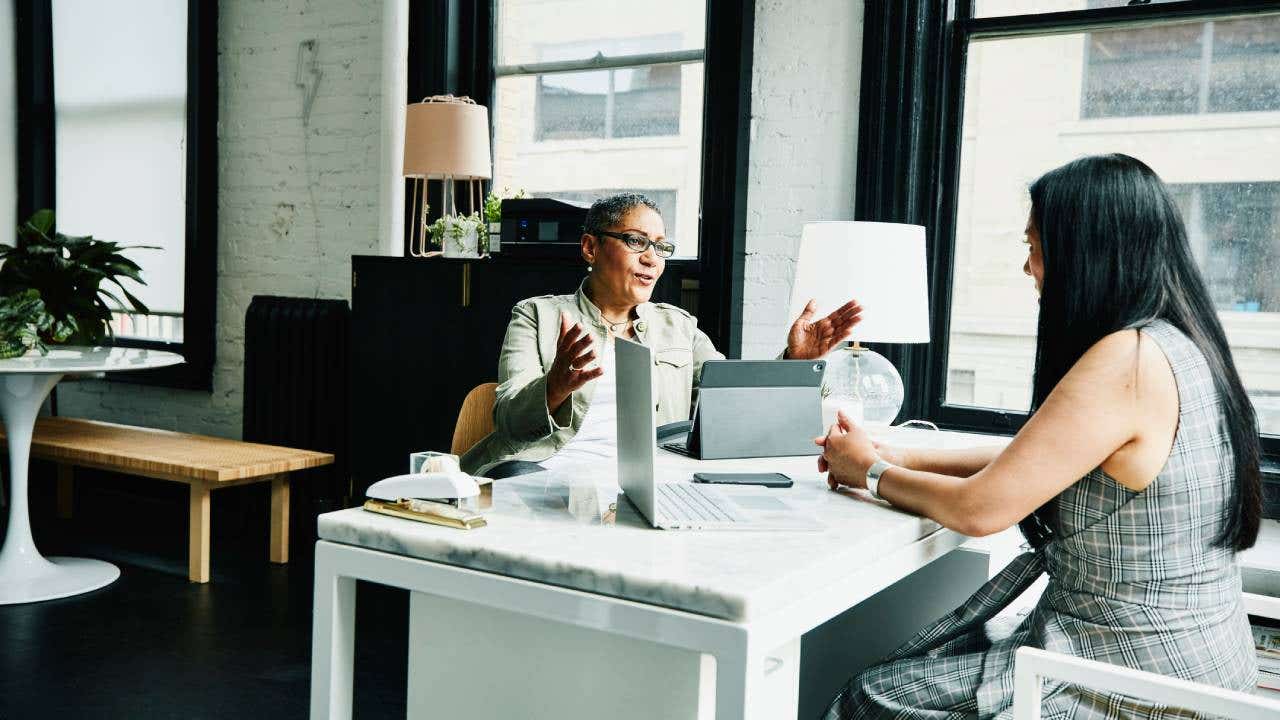 Female financial advisor in discussion with mature female business owner at desk in office