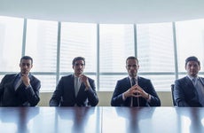 Row of stern businessmen sitting at conference table