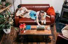 couple sitting together on the couch and working on laptop and phone