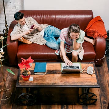 couple sitting together on the couch and working on laptop and phone