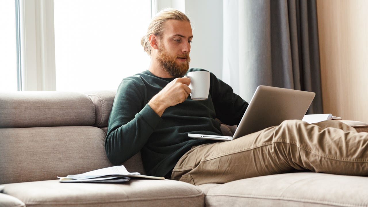 man sitting on the couch and working on laptop