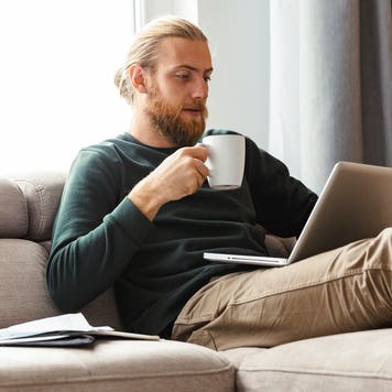person sitting on the couch and working on laptop