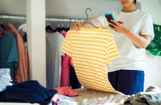 woman taking cell phone photo of a shirt from her closet