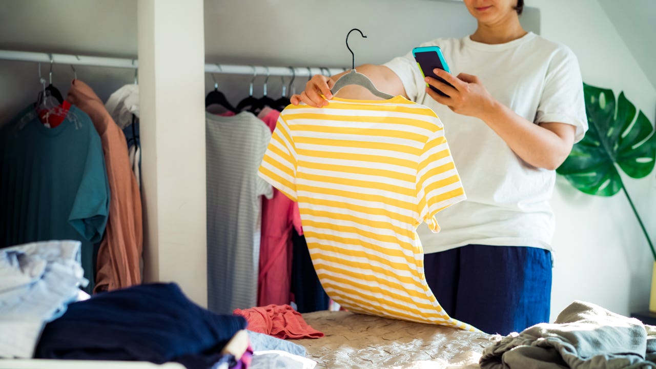 woman taking cell phone photo of a shirt from her closet