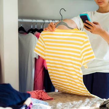 woman taking cell phone photo of a shirt from her closet
