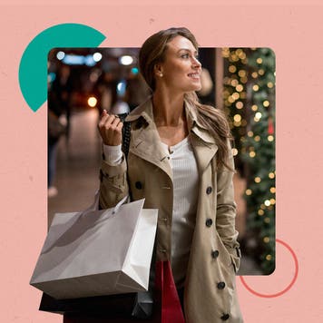 A woman doing Christmas shopping. There is a Christmas tree in the background and they are carrying a couple of shopping bags.