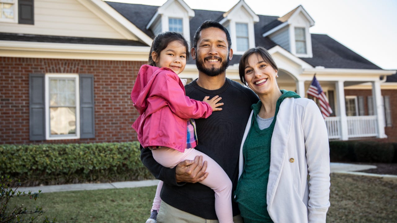 A family stands in front of their new house