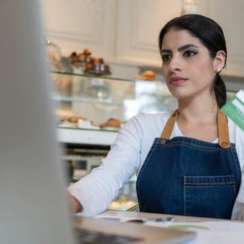 Bakery shop worker shopping online with her credit card using her laptop