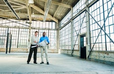 Businessmen reading blueprints in empty warehouse