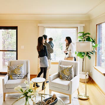 Wide shot of family looking at home for sale with real estate agent