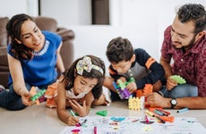 Smiling Hispanic/Latino family - mom, dad, daughter and son - at home drawing pictures and playing games together
