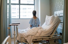 Female patient sitting on bed in hospital ward