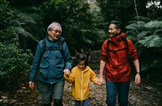 Three generation family hiking in rainforest in rain