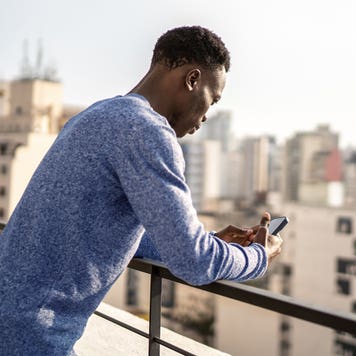 young man using his phone on a city rooftop