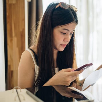 woman looking at her phone and bills