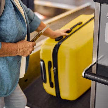 older woman picking up luggage