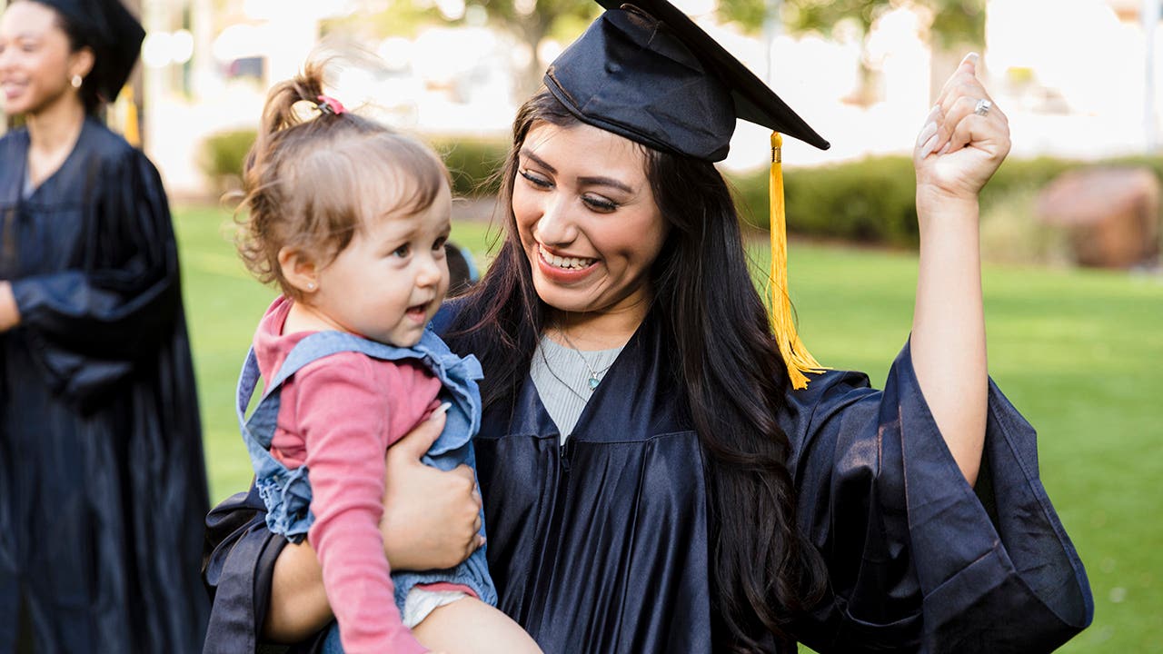 mom in graduation gown holding daughter