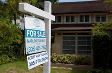 Suburban Florida home with trees, green lawn, white "for sale" sign outside
