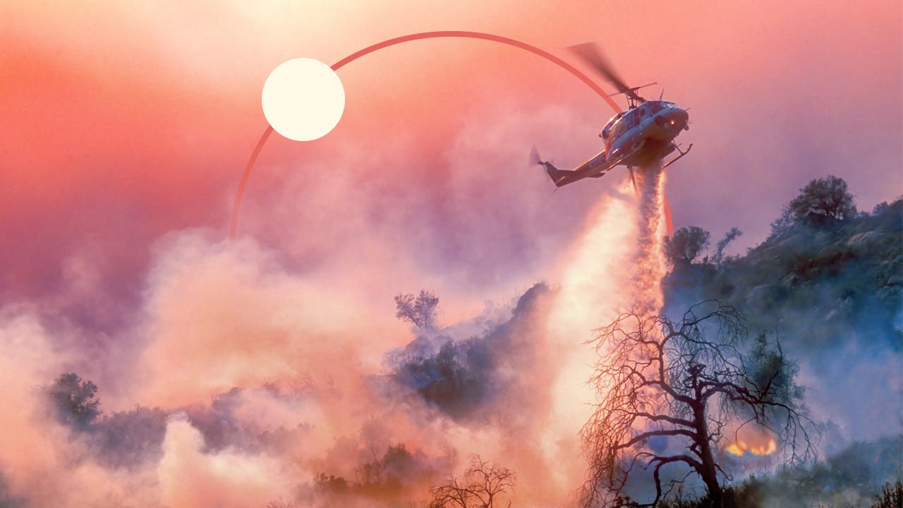 A helicopter dumping water on a forest fire.