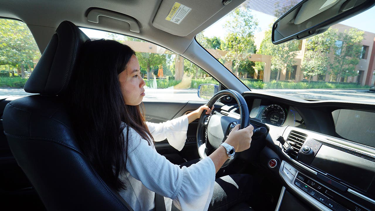 A young teenage girl sitting behind the wheel learning how to drive