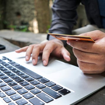 a person holding a card in front of a laptop